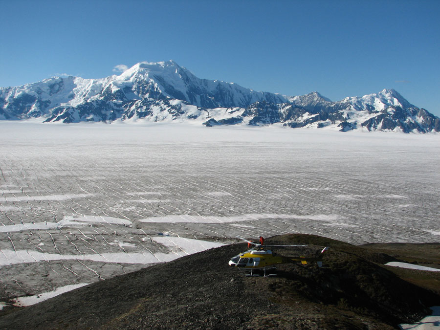 The Bagley ice field is believed to cover a large fault (Bagley fault), discovered by the STEEP project, which is thought to have become highly active in response to accelerated glacial erosion in the last million years. Resulting from differential rock motion across this structure, the large mountain in the background is moving up relative to the hill beneath the helicopter at about 10,000 feet per million years. Photo courtesy of Aaron L. Berger.