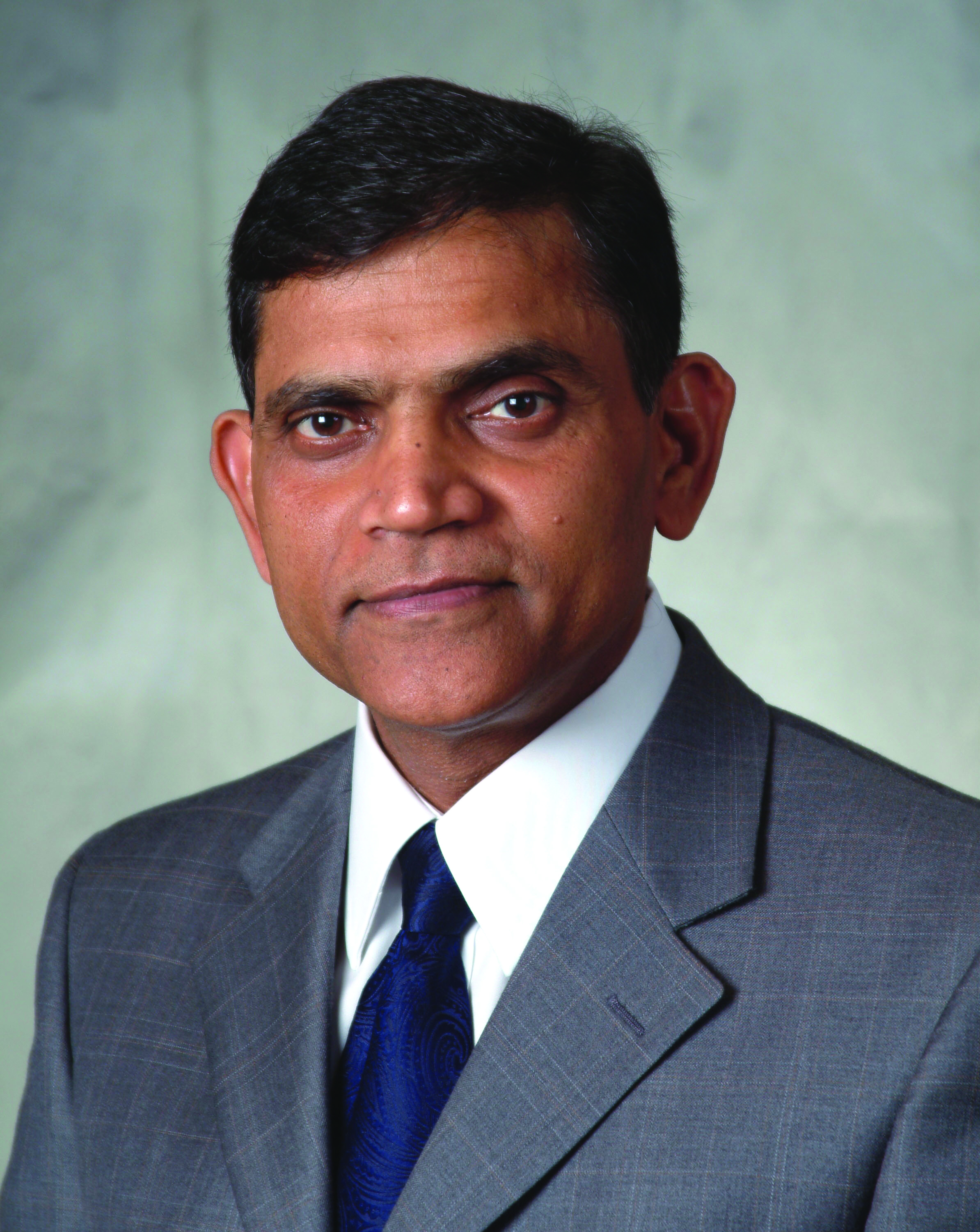 Janaki Alavalapati wearing a gray suite, blue tie, and white shirt