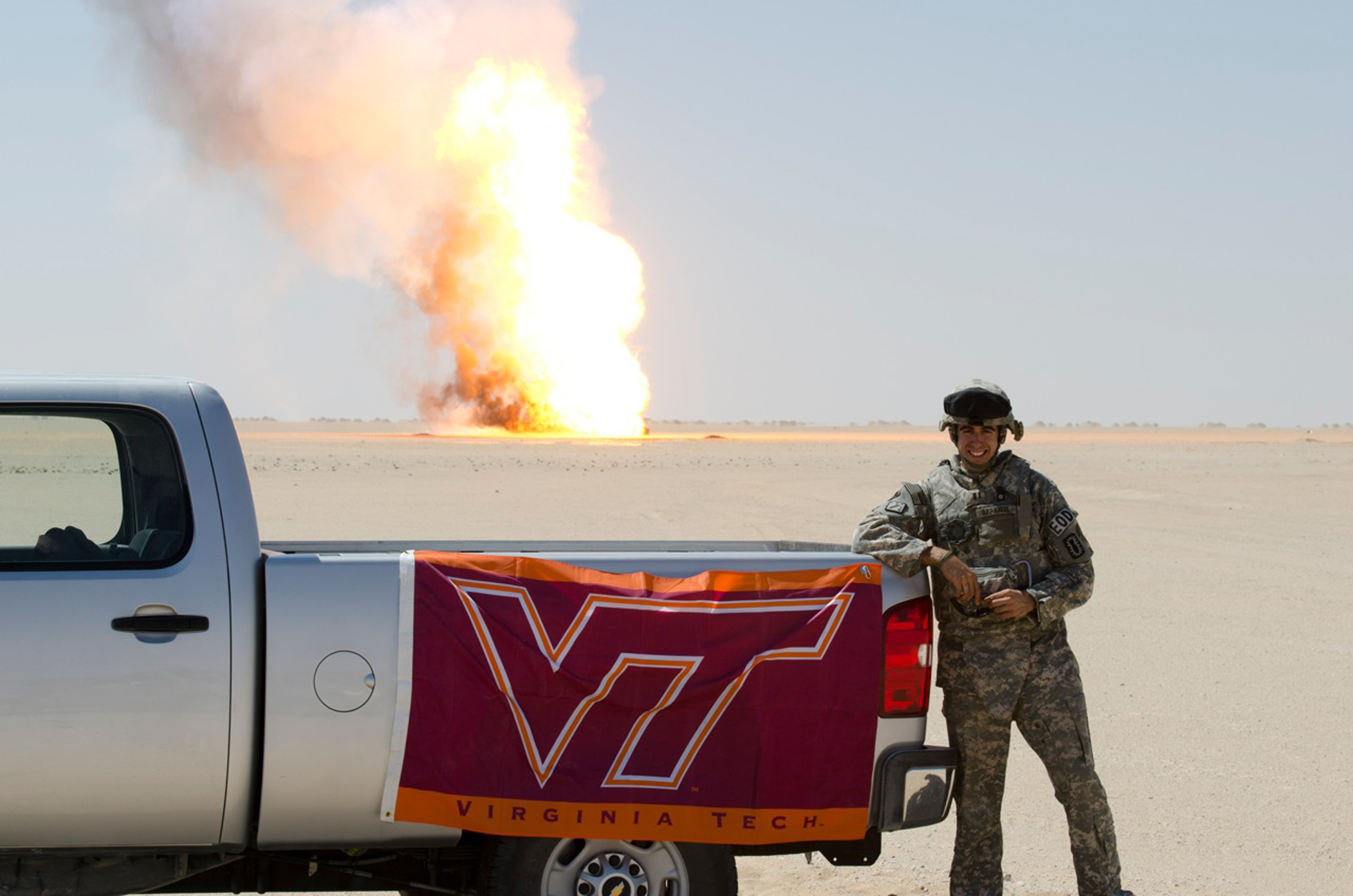 Capt. Amir Abu-Akeel, U.S. Army, Virginia Tech Corps of Cadets Class of 2006 standing in front a controlled explosion from his deployed location