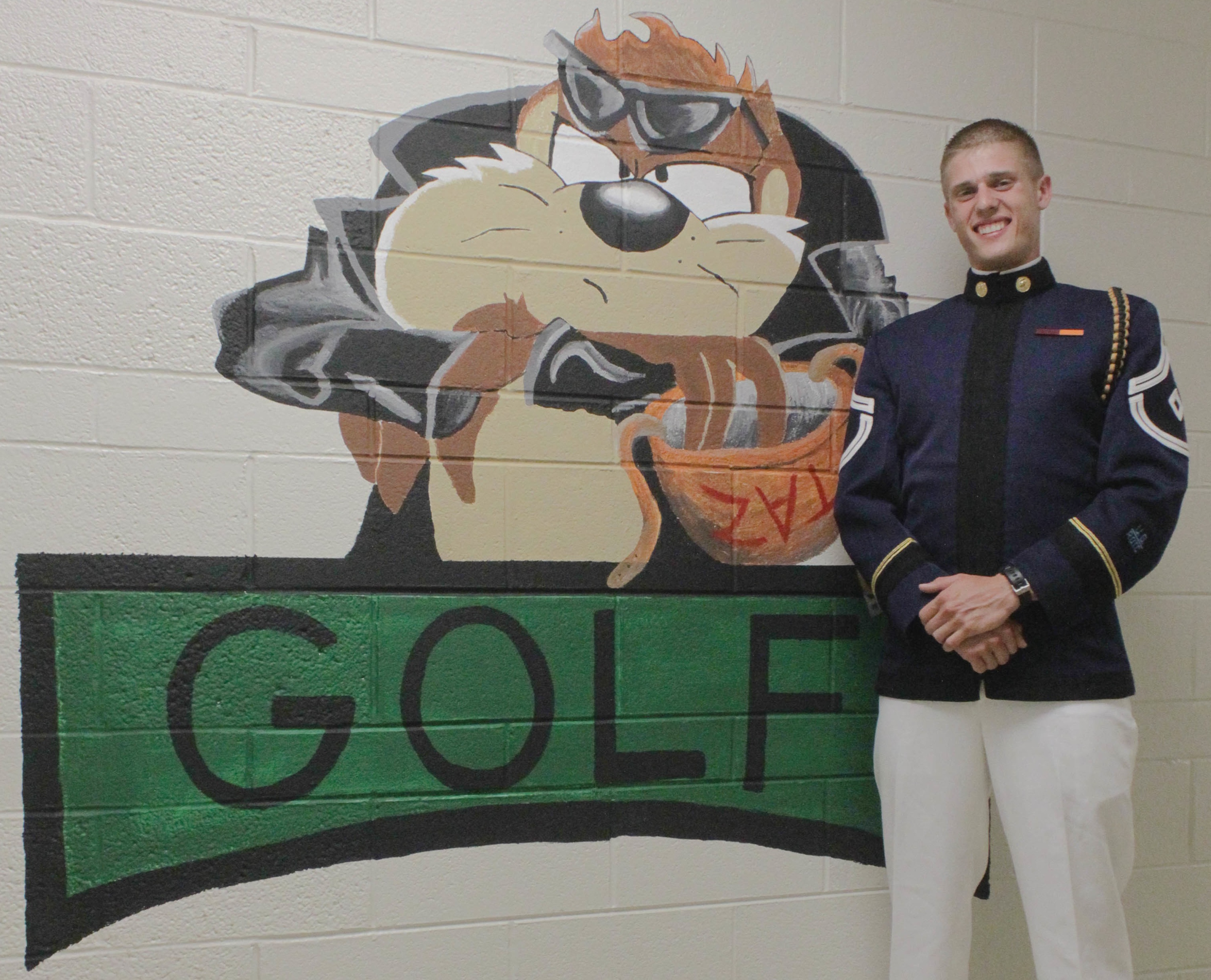 Cadet John Rogalo, the First Sergeant for Golf Company this fall standing in front of a mural in Golf Company