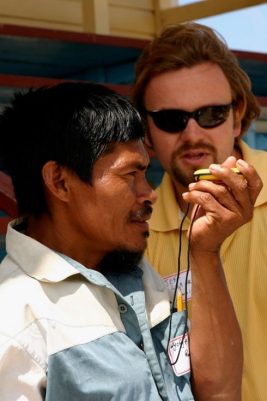 A man holds a compass while another man looks on