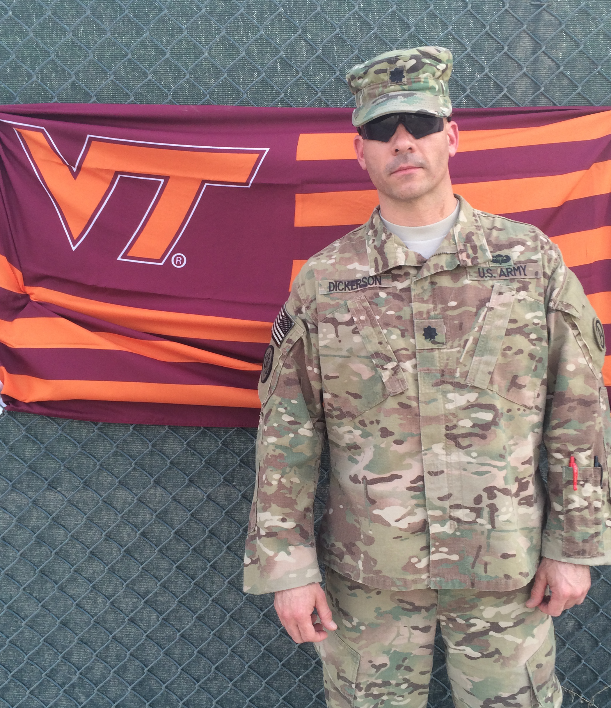 Lt. Col. Kelly Dickerson, U.S. Army, Virginia Tech Corps of Cadets Class of 1995 in front of a VT flag.