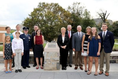 Family members gather with Virginia Tech Corps of Cadets representatives around a plaque recognizing Peter C. Snyder, a member of the corps’ Class of 1958, at the Peter Caldwell Snyder Flagpole Plaza. From left are Stacy Snyder, her husband, Lawrence Mason, and their children Anna and Levi Mason; Commandant of Cadets Maj. Gen. Randal D. Fullhart; university President Tim Sands and Laura Sands; Georgia Anne Snyder-Falkinham and her husband, Professor Joseph O. Falkinham; and Michael Snyder, his wife, Kristi Snyder, and their children Julianne and Justin Snyder.