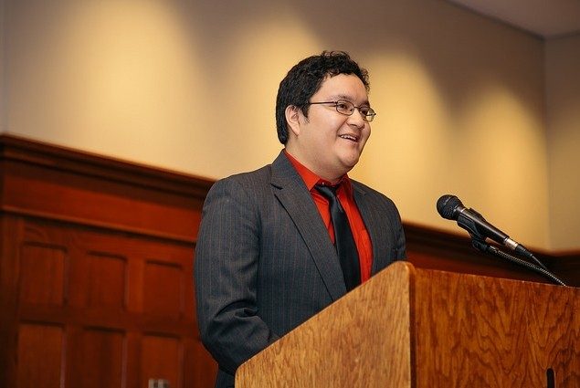Juan Hernandez offers remarks behind a podium in Owens Banquet Hall at Virginia Tech.