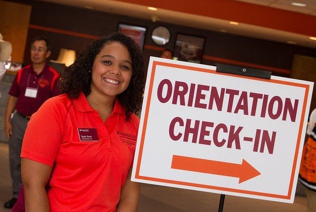 Taylor Swan poses beside a sign that reads "Orientation Check-In" in Squires Student Center.