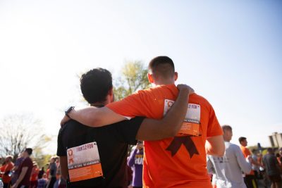 Two young men with runners bibs, stand arm in arm