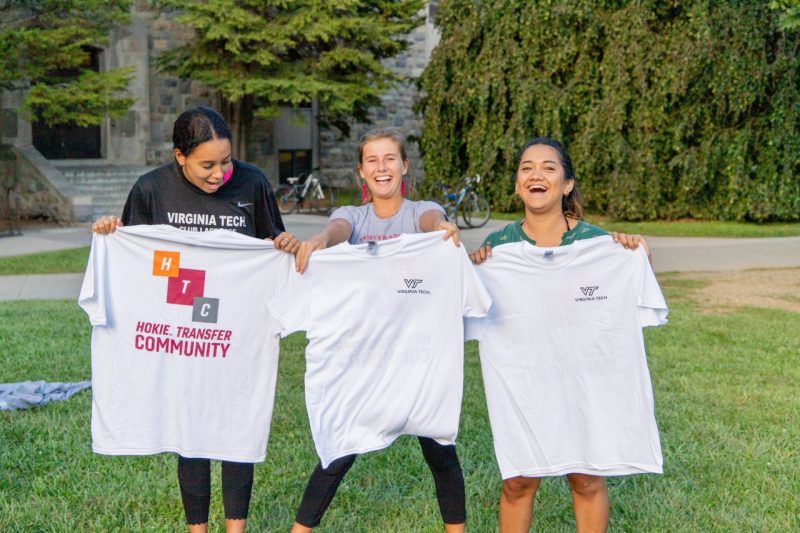 Three female students hold up t-shirts from the Virginia Tech Hokie Transfer Community.