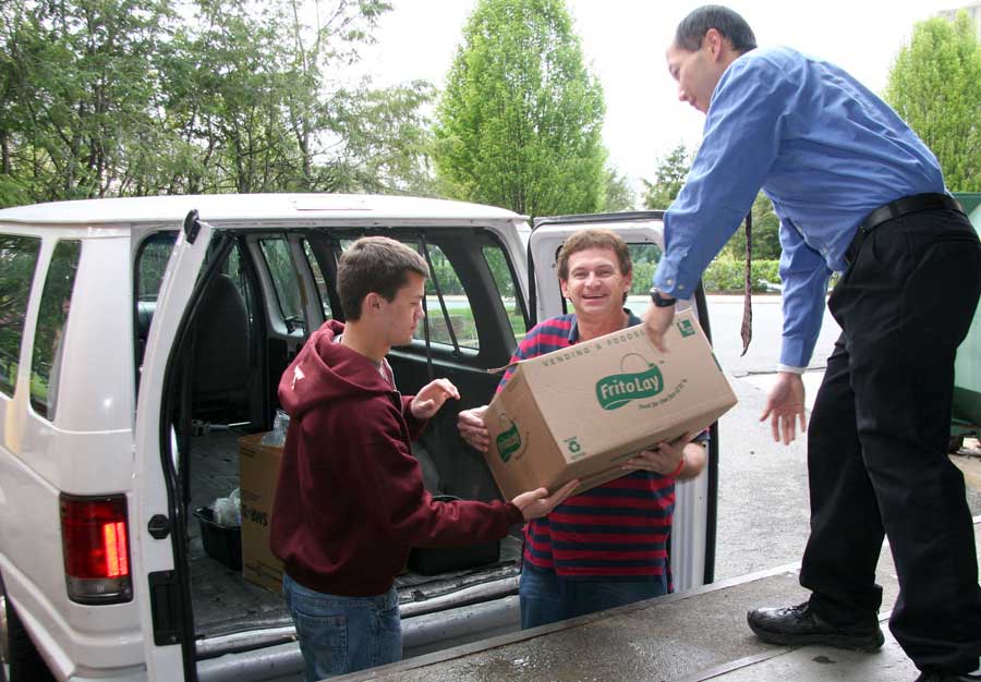 Virginia Tech freshman Jacob Moyer (left) and Salvation Army volunteer Craig Woods (center) pick up food items packaged for donation from Operations Manager Tom Fong at an Au Bon Pain restaurant on campus.