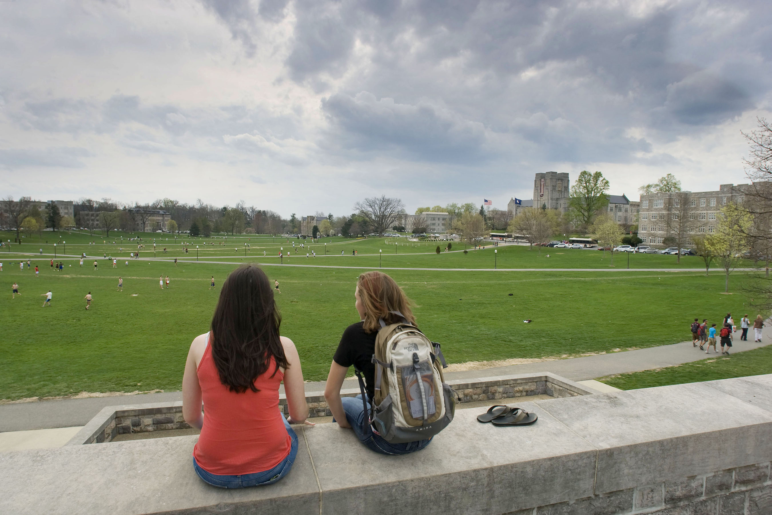 Students sit on the War Memorial Chapel wall and overlook the Drillfield.