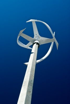 Dramatic photo of a white verticle wind turbine against a blue sky
