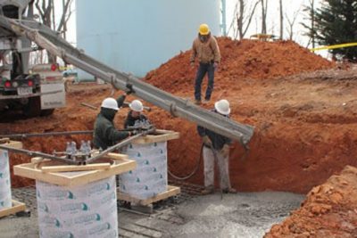 Construction workers are pouring cement to prepare a support base where a new radio tower will be built.