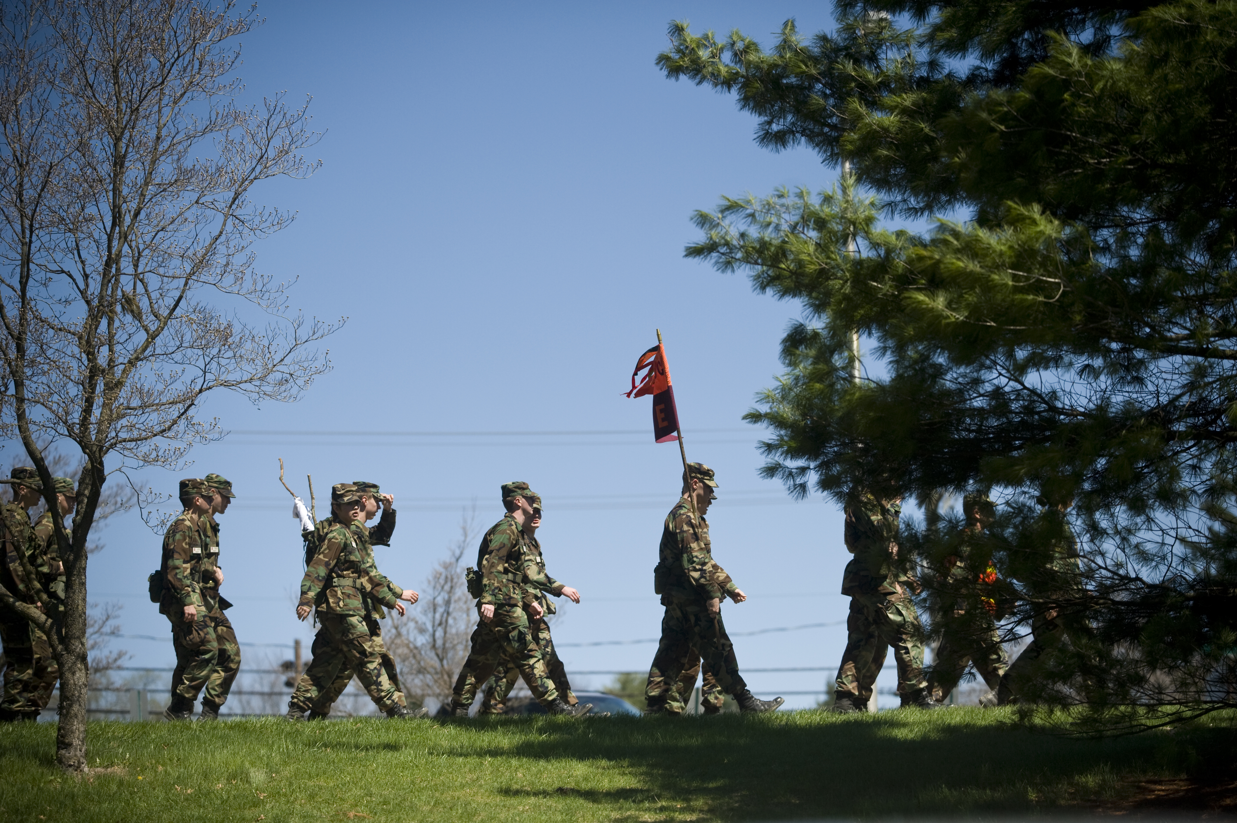 Corps members carry a flag and march in formation