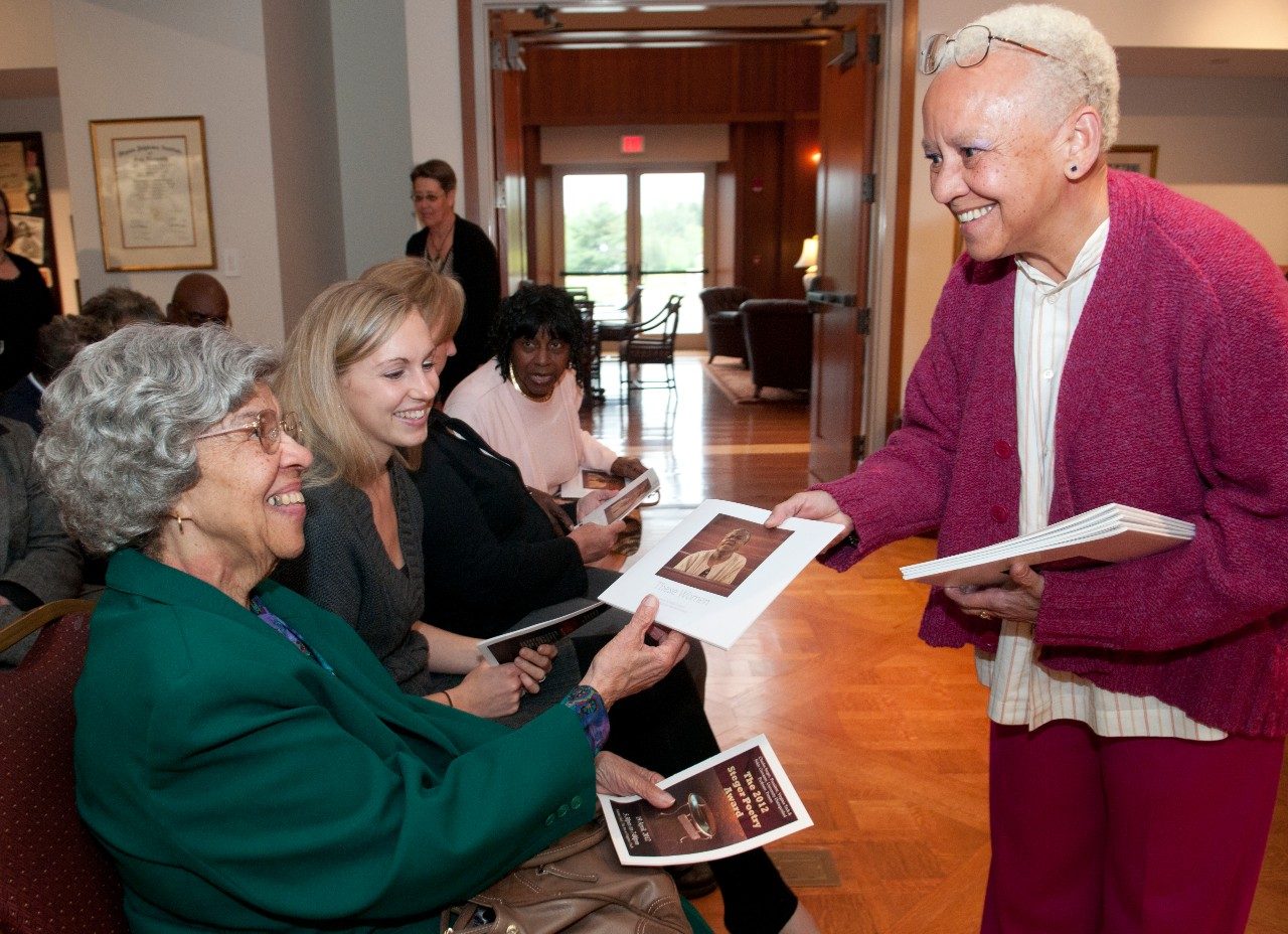 World renowned Virginia Tech poet Nikki Giovanni presents Esther Jones, lifetime resident of Wake Forest, with a copy of the illustrated poem, "These Women." Morgan Cain Grim, the 2009 Steger Poetry Prize award winner looks on along with Benzena Eaves, another community member of Wake Forest.