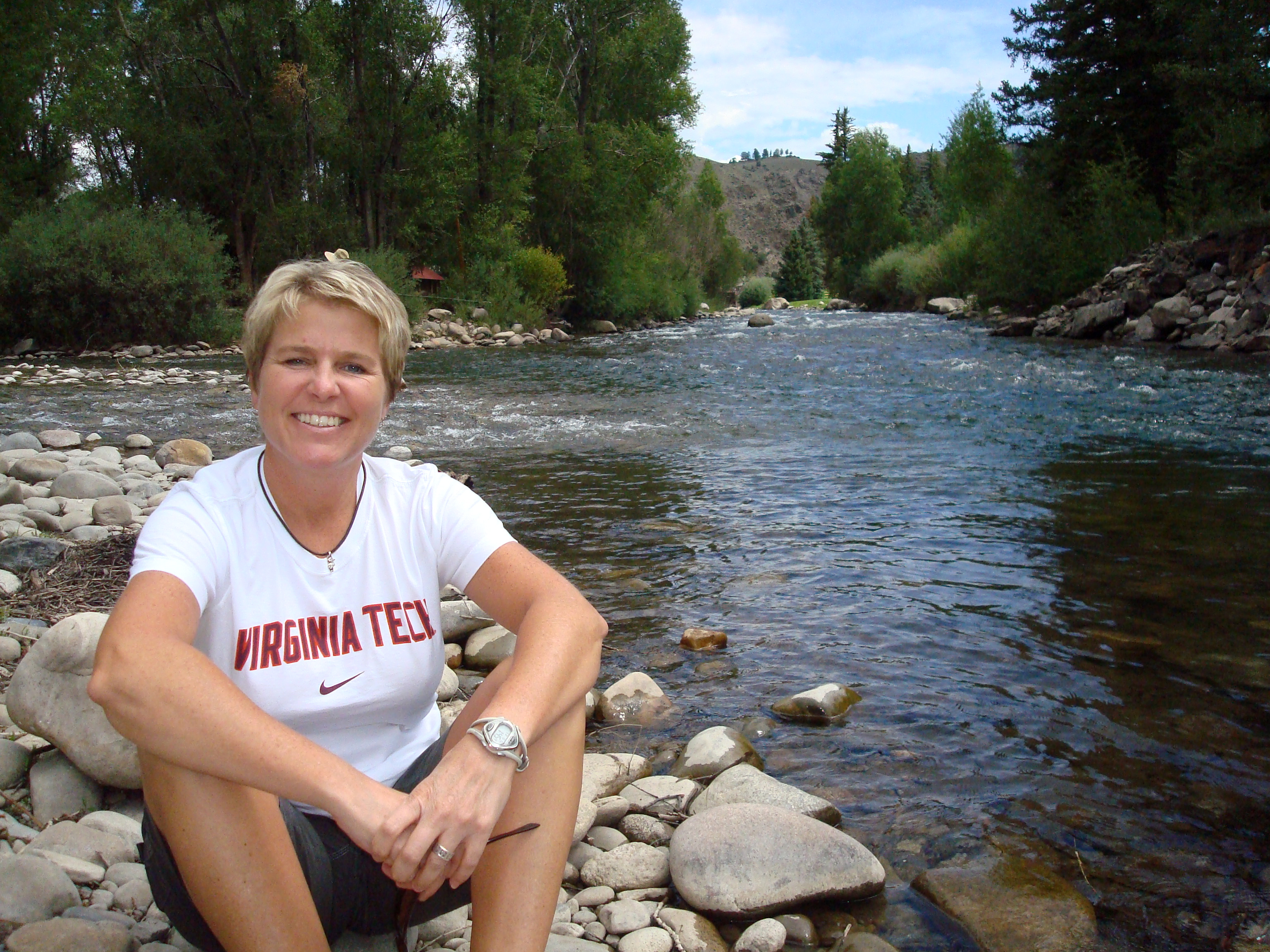 Jill Knoll sits on a rock next to a river.
