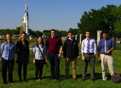 Seven students stand in front of a rocket at NASA's Johnson Space Center
