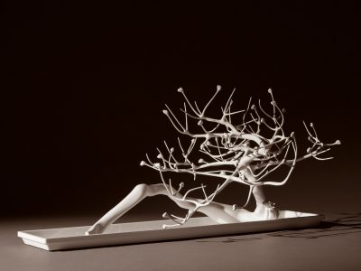 A white sculpture resembling a twisted, budding tree without leaves. 