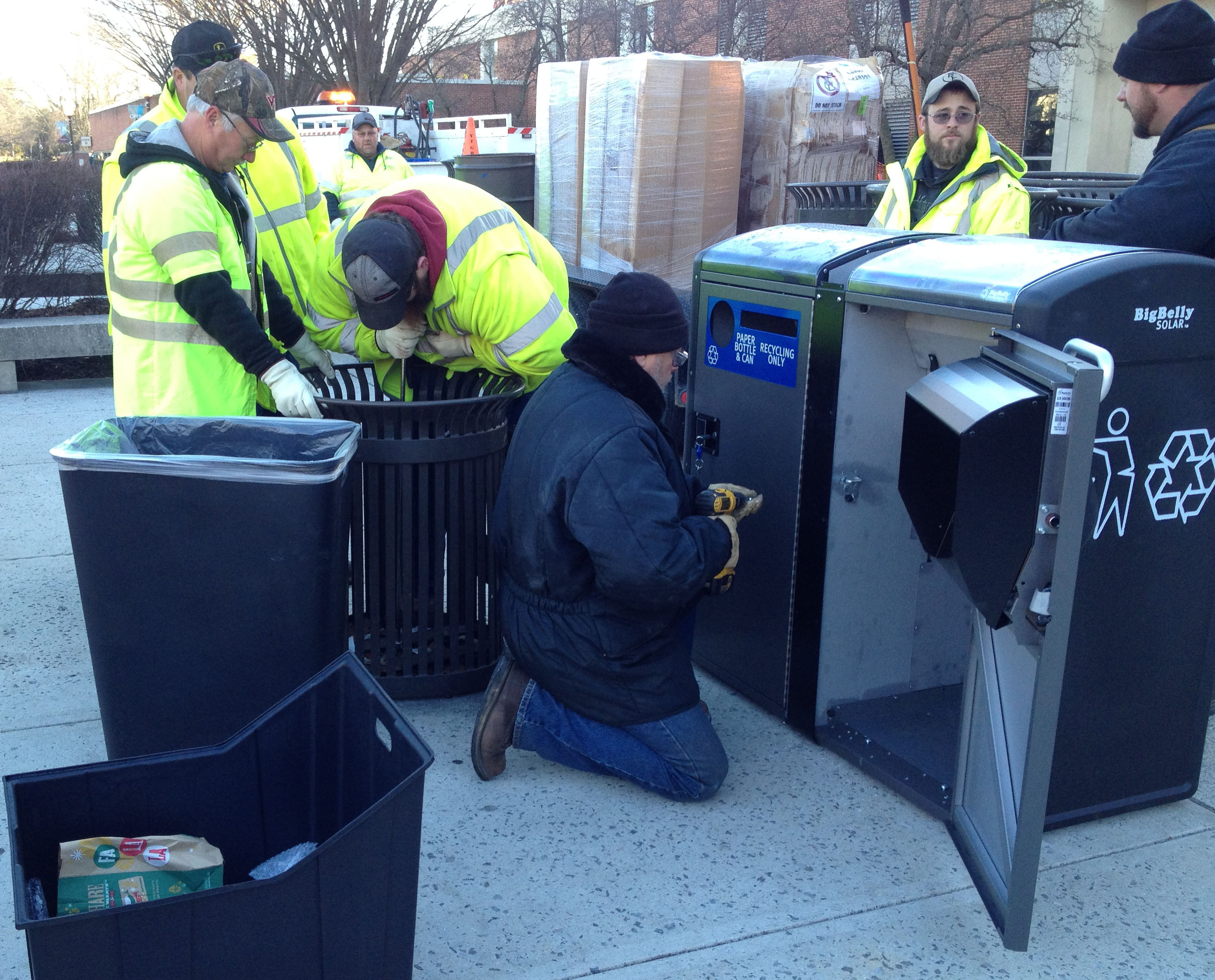 crews installing new big belly trash and recycling containers