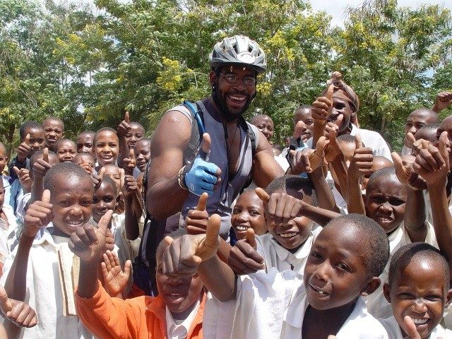 David Sylvester poses with some children during his transcontinental cycling trip across Africa.