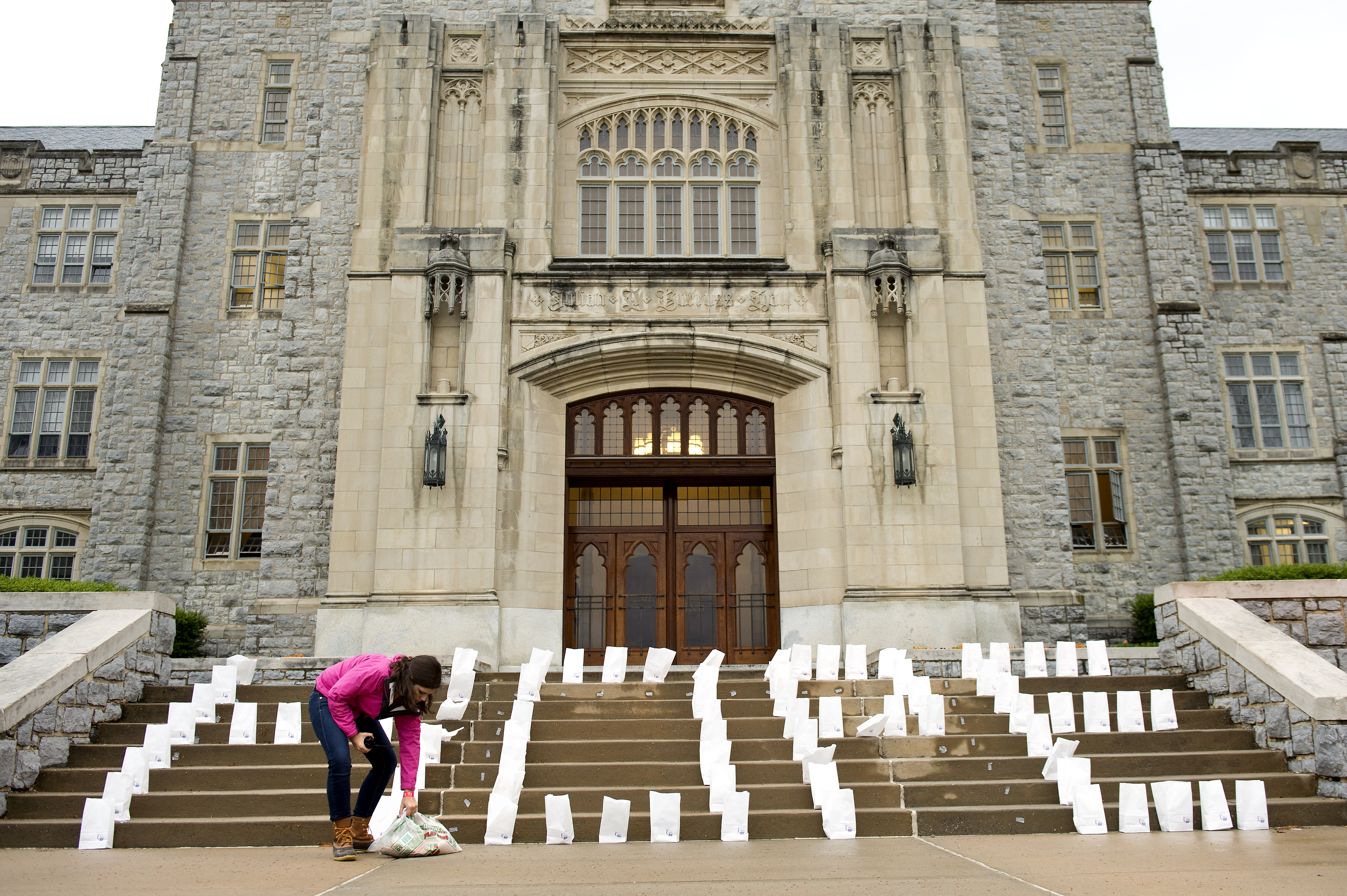 A student places candles on the steps of Burruss Hall.