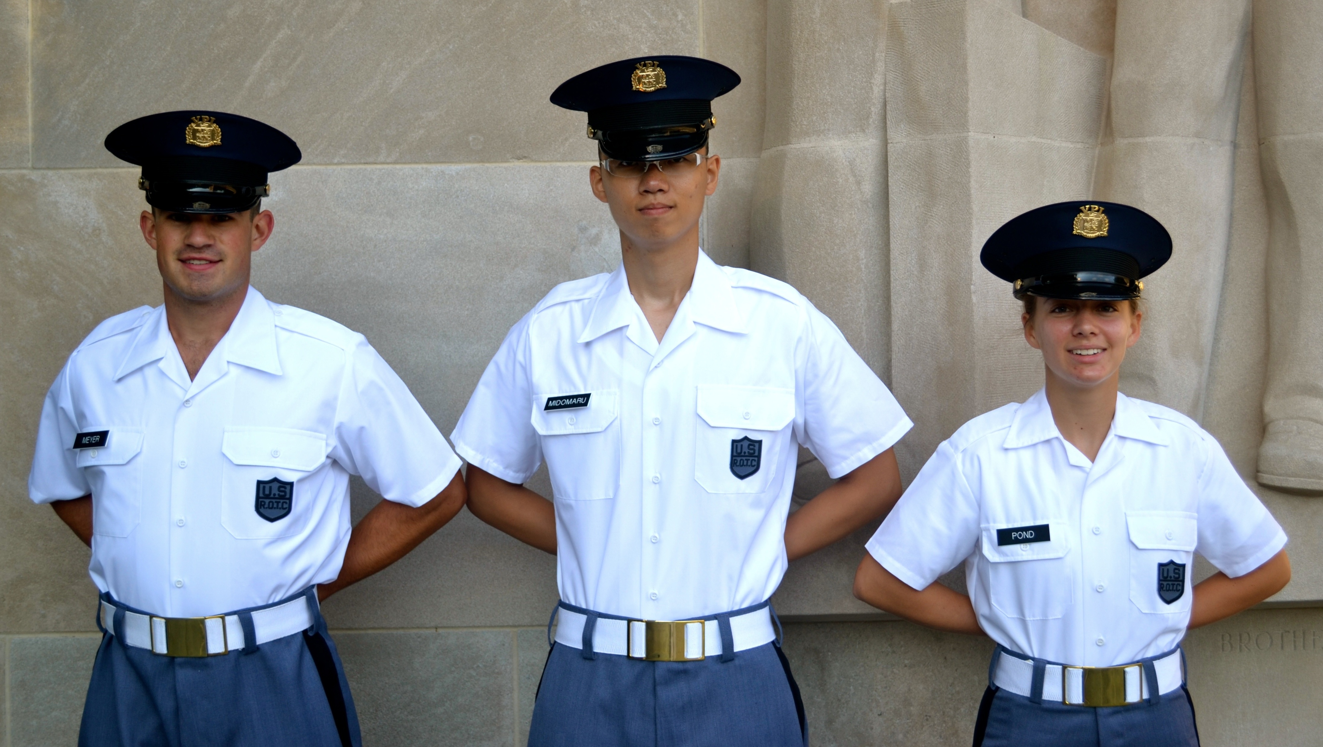 From left to right are Cadets Thomas Meyer, Ronald Midomaru, and Joelle Pond standing in front of the Brotherhood Pylon.