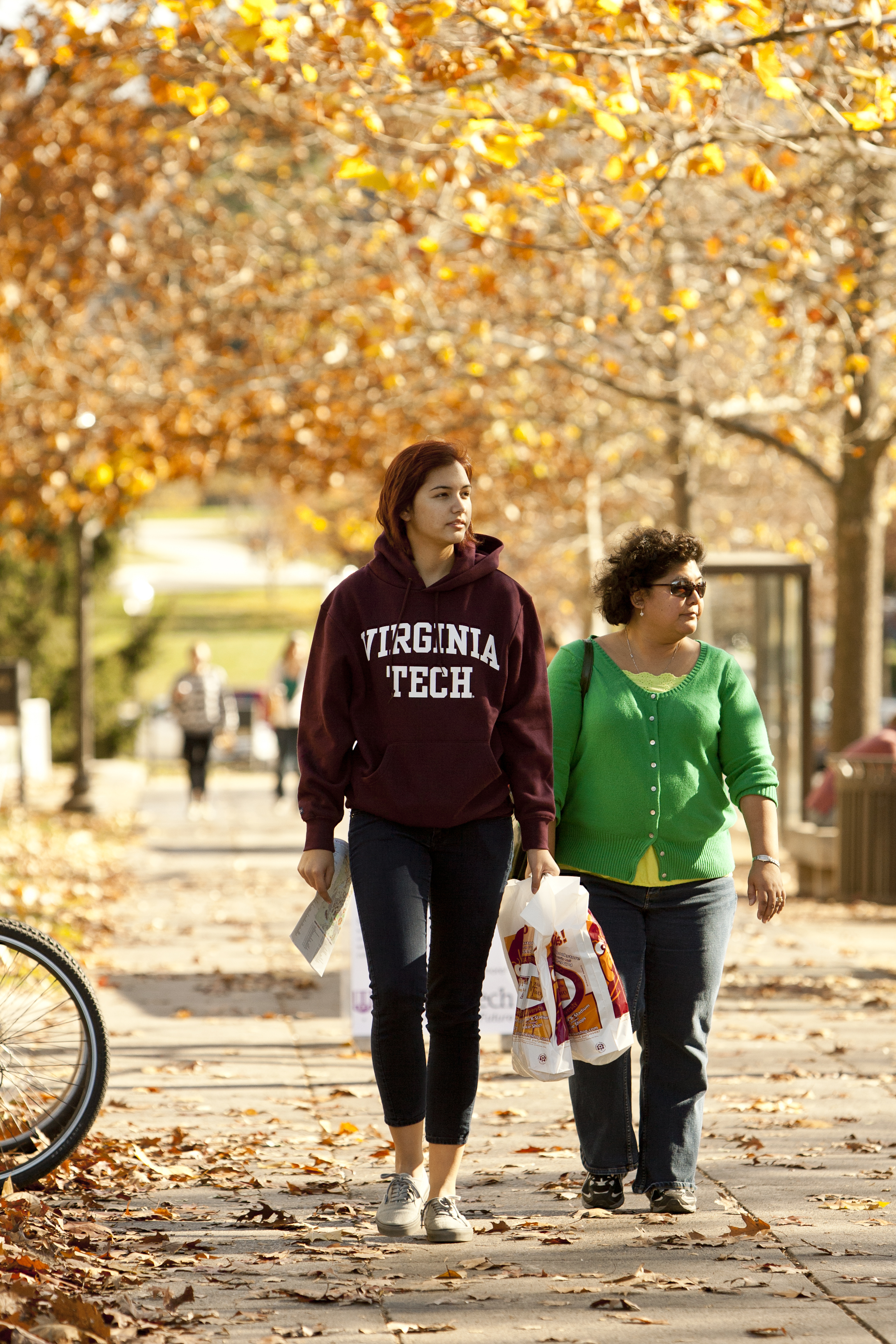 Student and mother walking under autumn leaves.