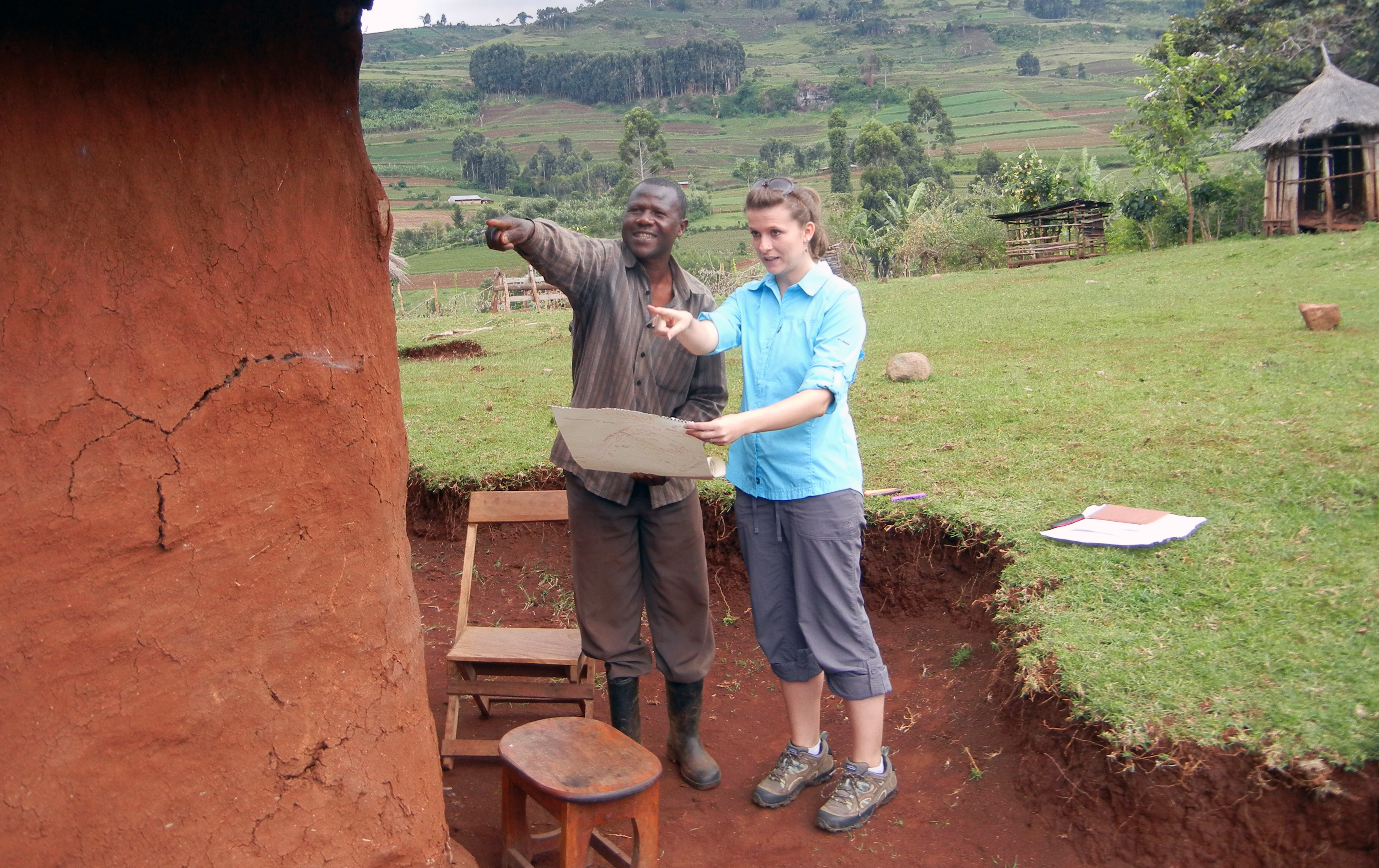 A Virginia Tech employee stands next to a farmer with a map in Uganda.