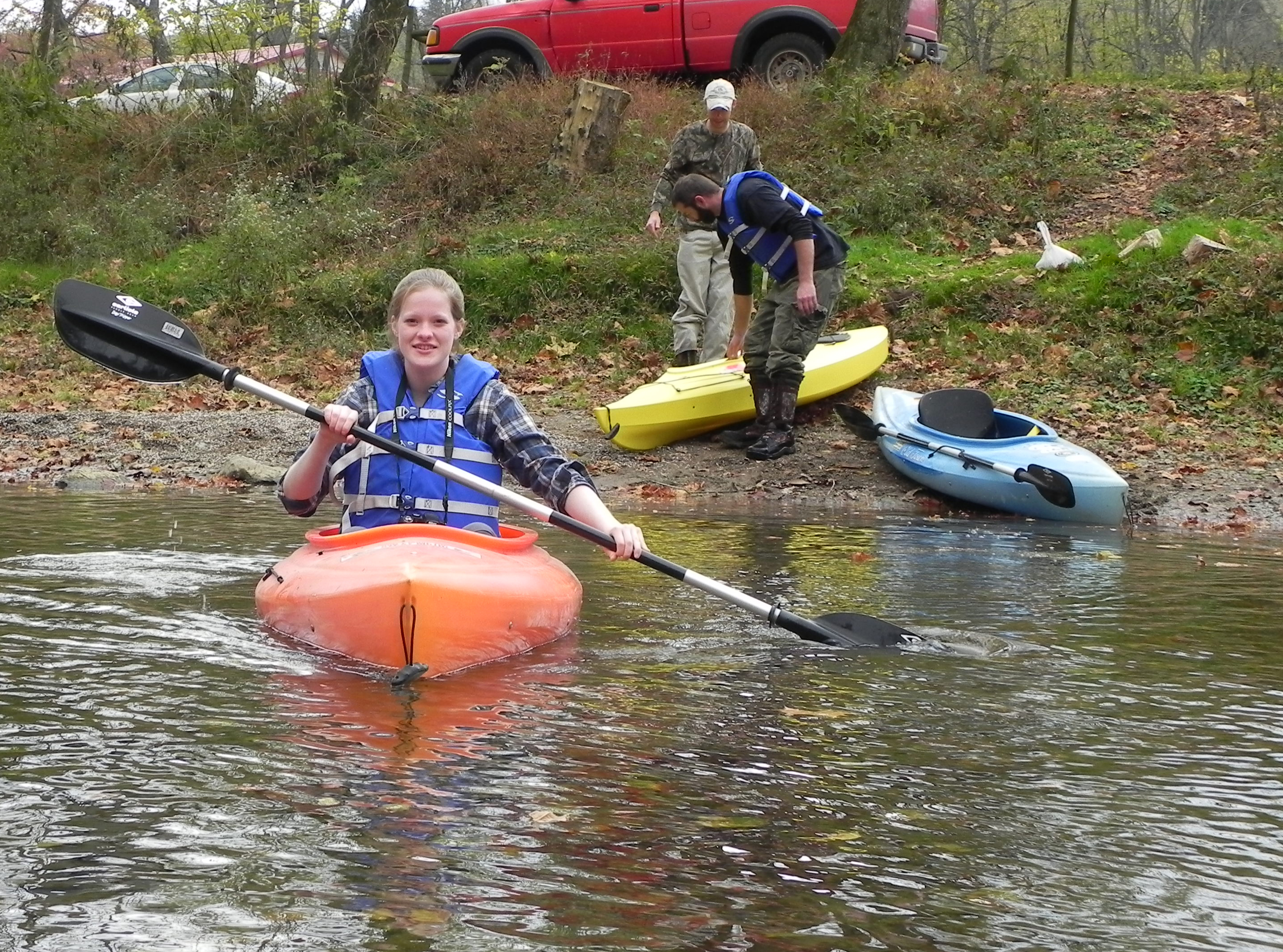 Student in kayak with other students on riverbank