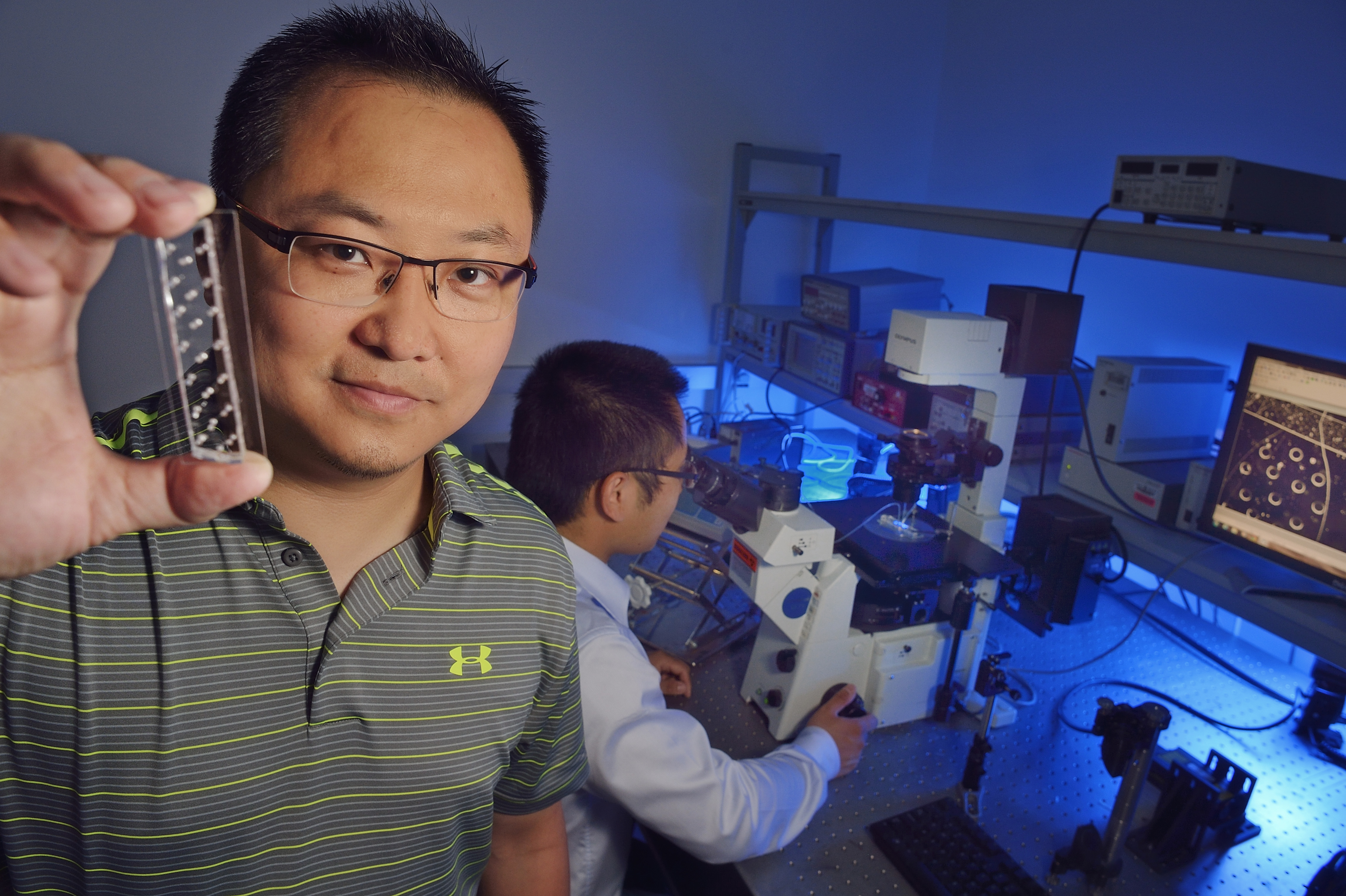 Chang Lu holds microfluidic chip used in research.