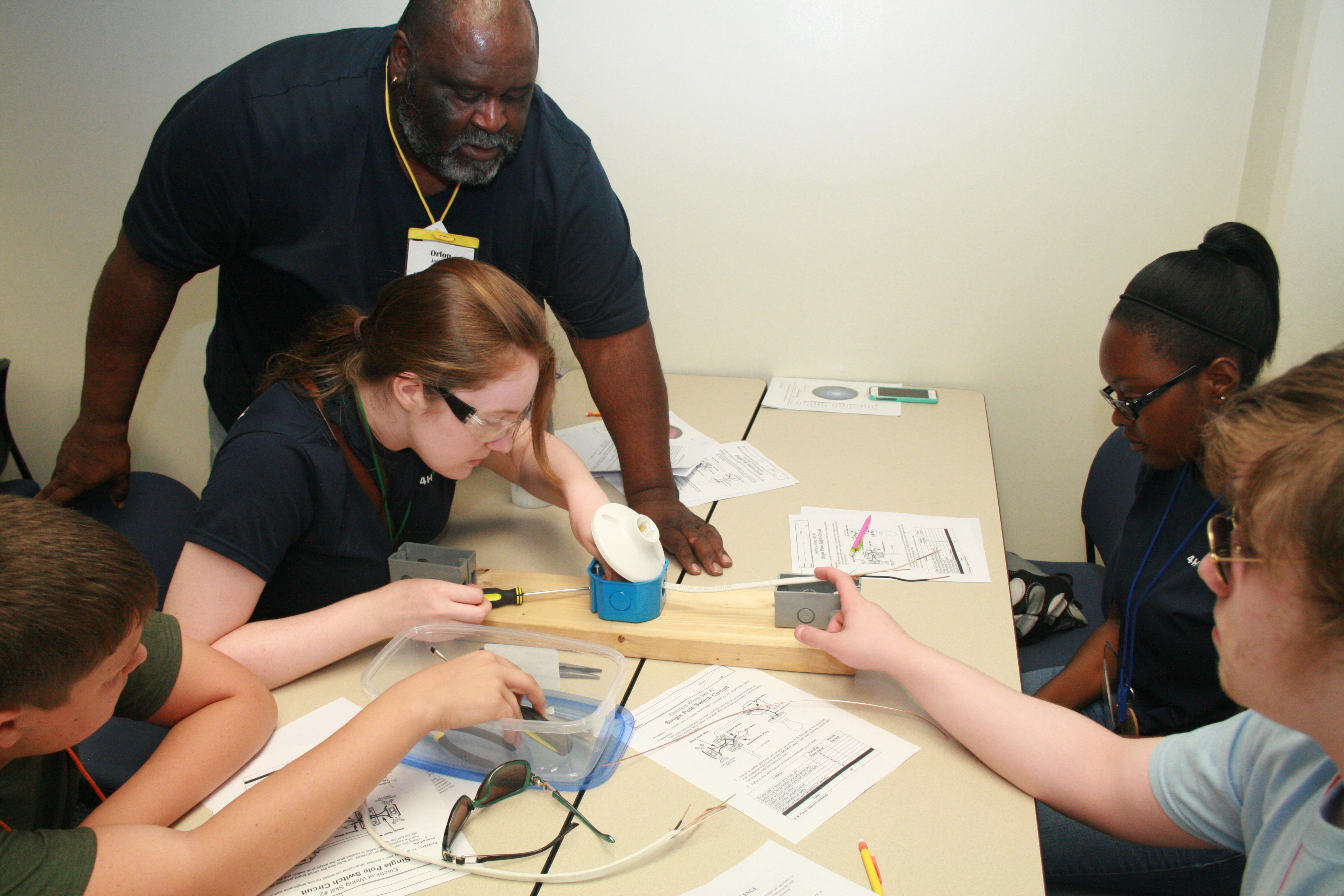 Students at a table of four study the base of an electric outlet.