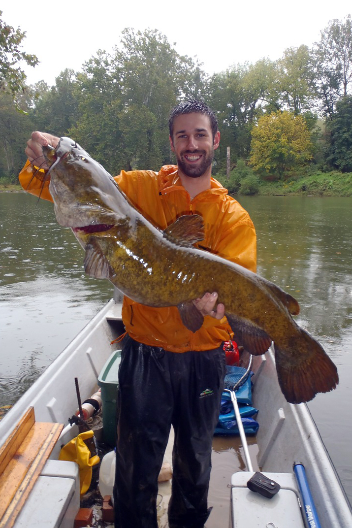 Ben Dickinson holding a large catfish along a river