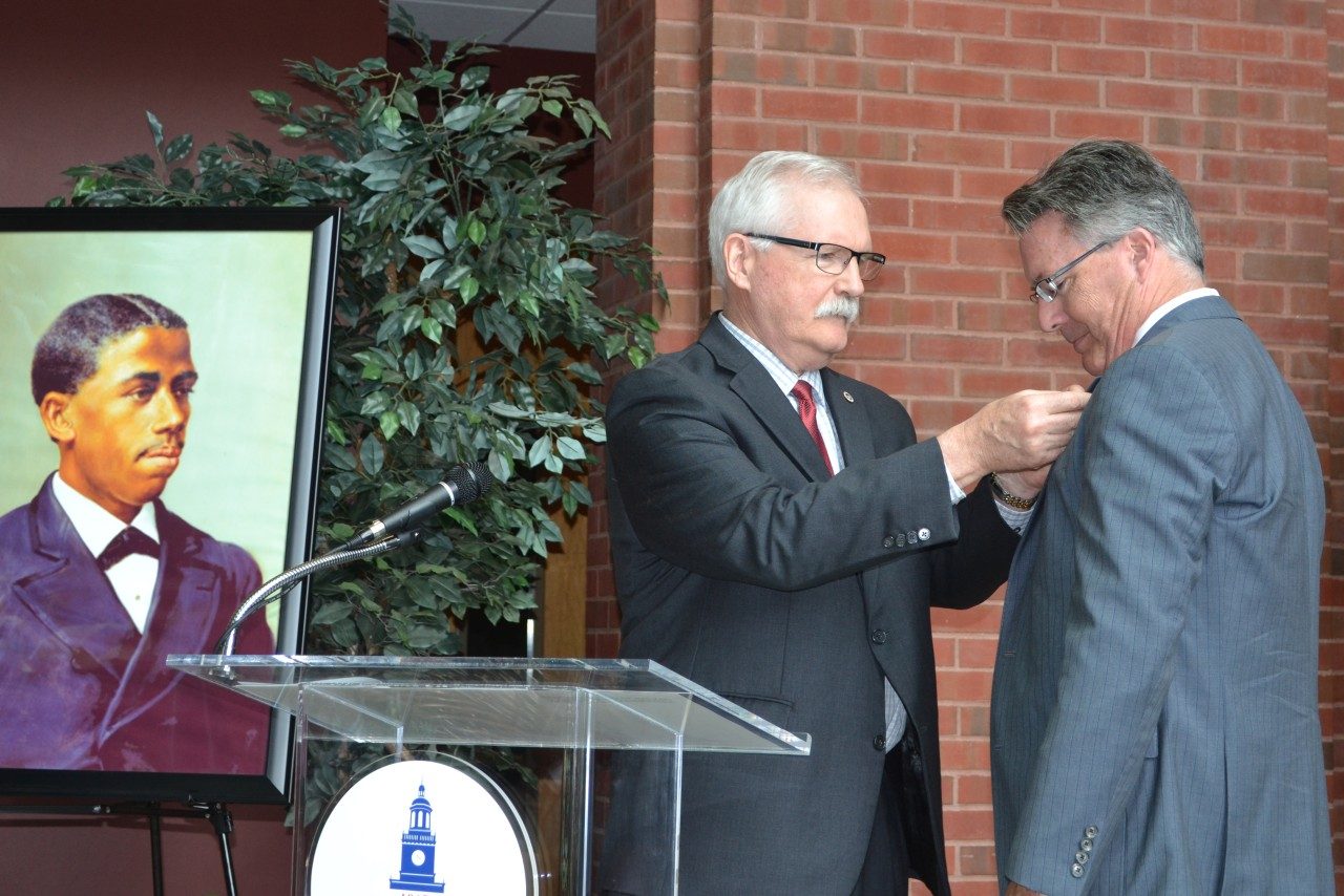 Howard University Associate Provost Gary L. Harris attaches a pin to President Tim Sands' lapel at the Bouchet Forum, where Sands received the Bouchet Legacy award