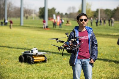 Electrical and computer engineering doctoral student Kevin Yu led a team that operated a coordinated pair of unmanned vehicles: the drone in this hands and the ground vehicle behind him. 