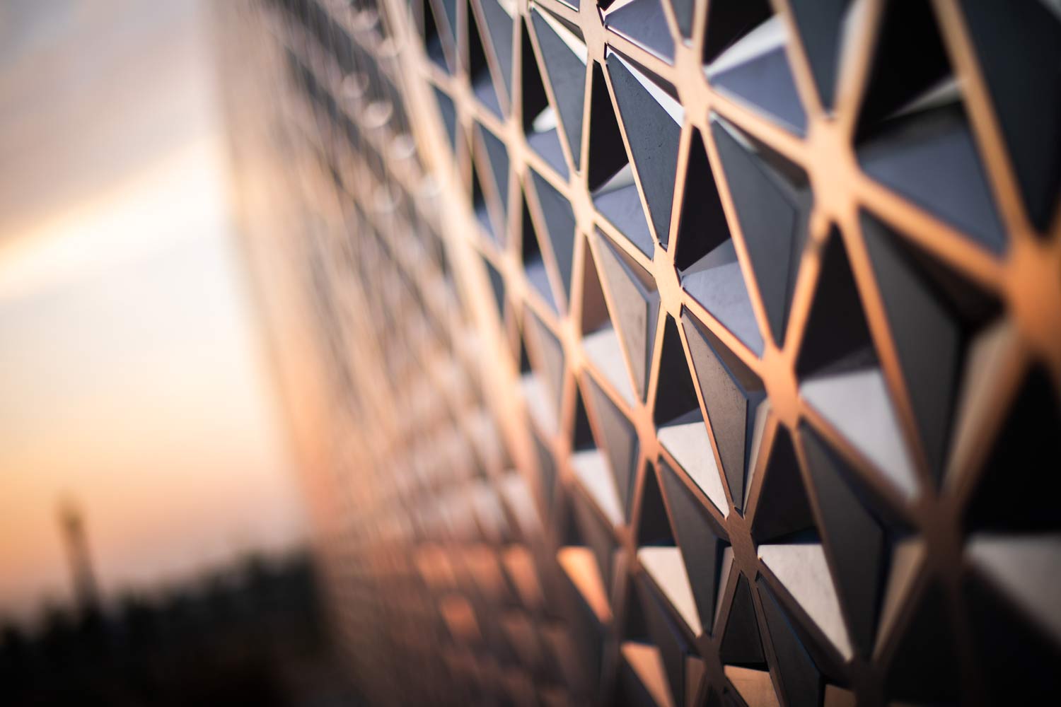 Vivid orange light paints a screen wall that is cut with an intricate pattern.