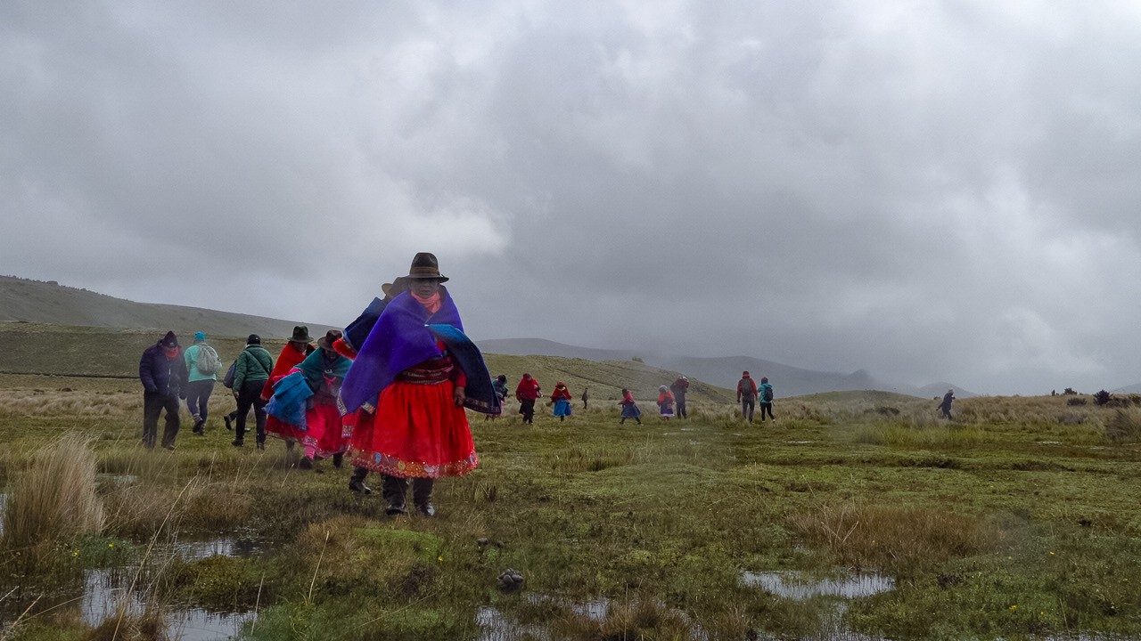 Locals walk through marsh wearing traditional Andean clothing.