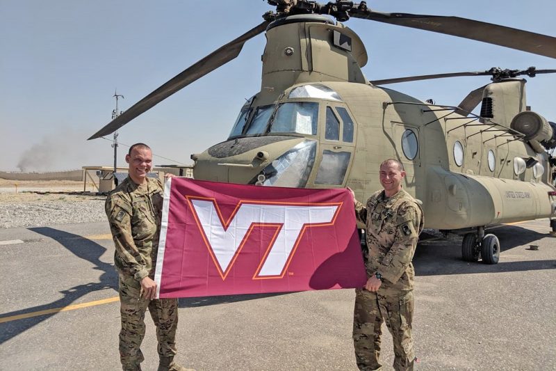 U.S. Army Chief Warrant Officer Chris Toler, at right, holds a Virginia Tech flag with 1st Lt. Marco Peterson.