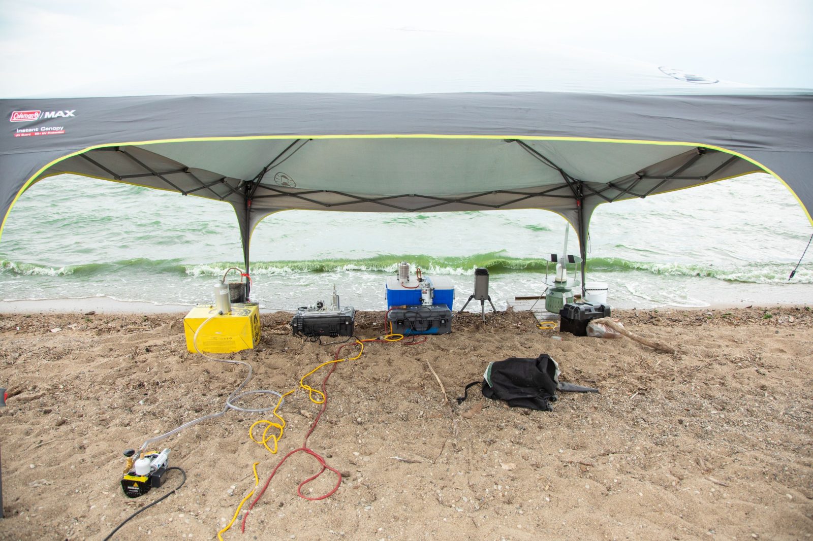 A large grey tent is located on the shoreline of Grand Lake St Marys, Ohio. Under the tent, aerosol-monitoring equipment is collecting data on harmful algal blooms. Courtesy of Christina+David.