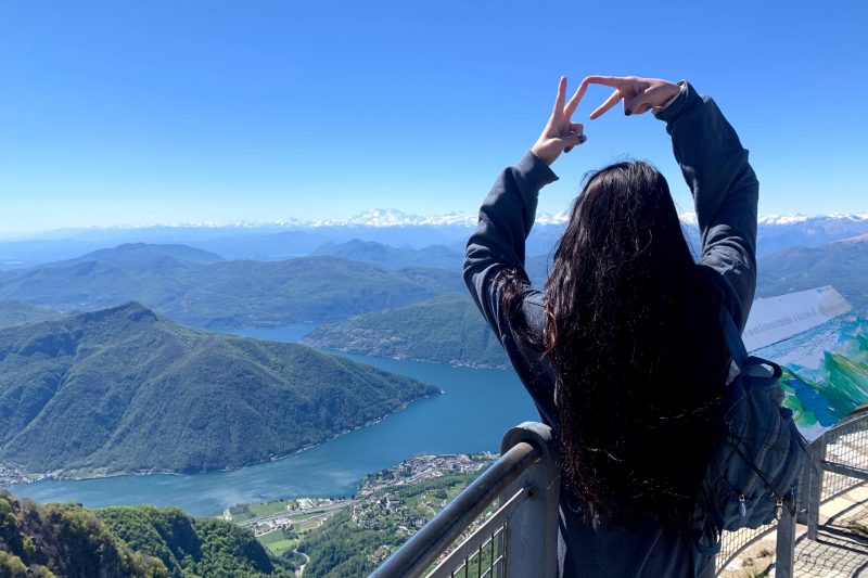 Student holds up a VT sign as she overlooks a lake in Switzerland.