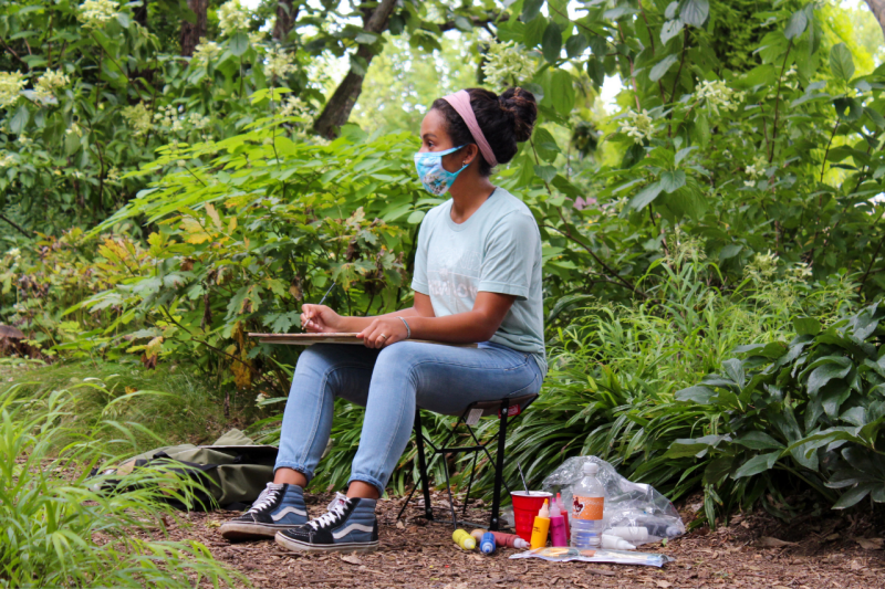 A student paints at the Hahn Horticulture Garden