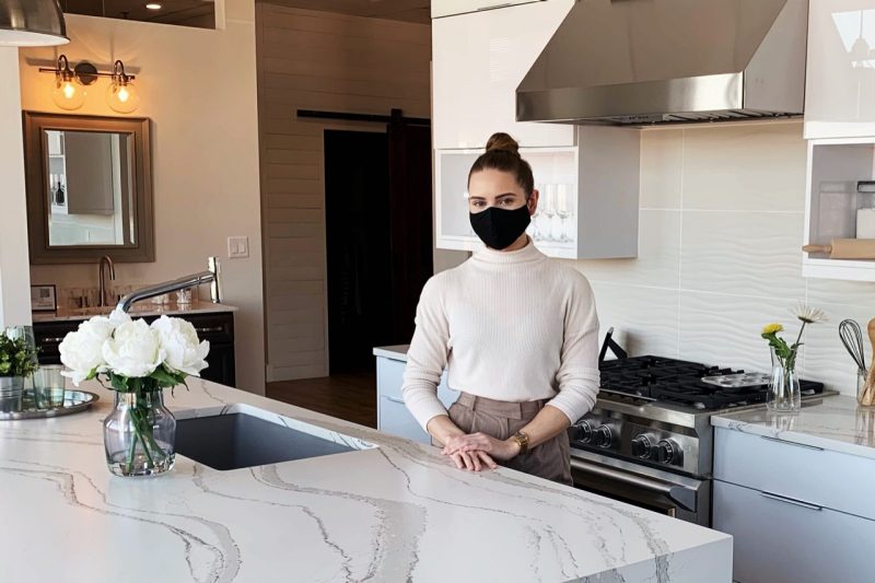 Taylor Olson stands in a kitchen wearing a mask.