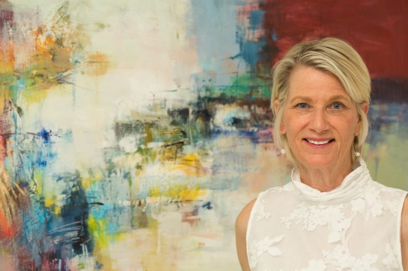 Kay Winzenried stands in front of an abstract painting
