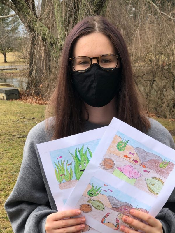 With illustrations from her children's book in-hand, Amelia Schmidt stands near the Duck Pond. 
