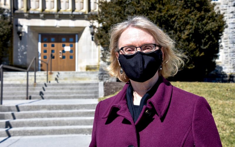 Martha Ann Bell, a newly appointed University Distinguished Professor in the  Department of Psychology, poses wearing a COVID mask in front of Williams Hall. Photo by Melissa Vergara. 