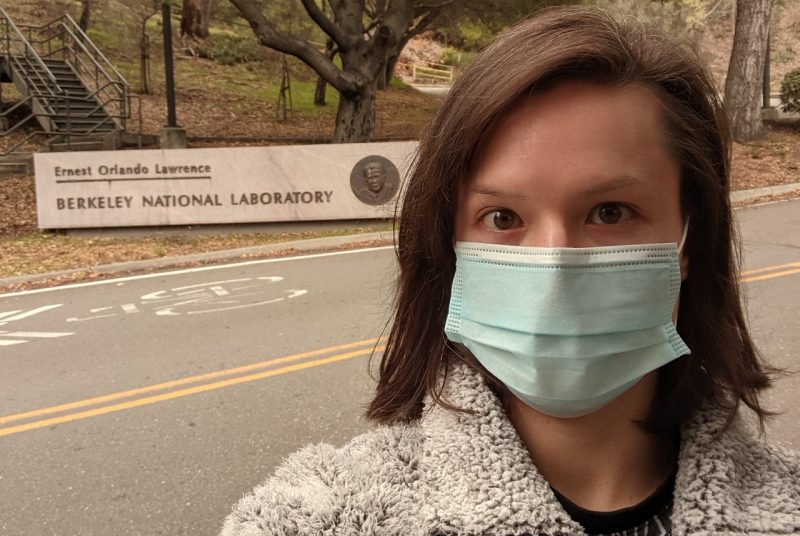 Melissa Novy is wearing a mask and standing in front of a sign for Lawrence Berkeley National Laboratory