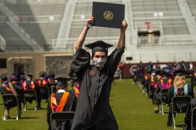 A graduate student holds up a degree