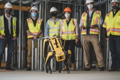 Spot the robotic dog surrounded by construction and research leaders