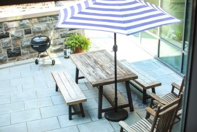 Faculty suite patio with a white and blue striped umbrella, picnic table and chairs and a grill