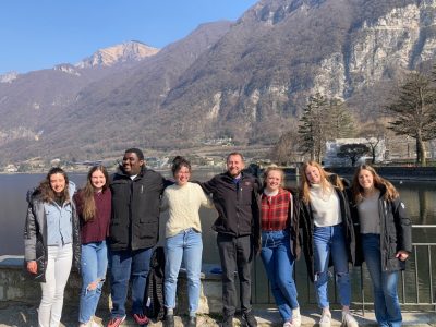 College of Architecture and Urban Studies student group outside in front of water and mountains in Riva San Vitale, Switzerland