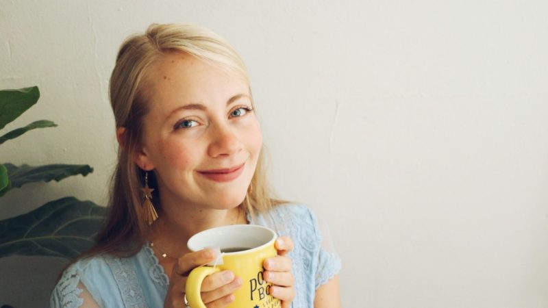 Morgan Long smiles at the camera while holding a mug of hot tea.