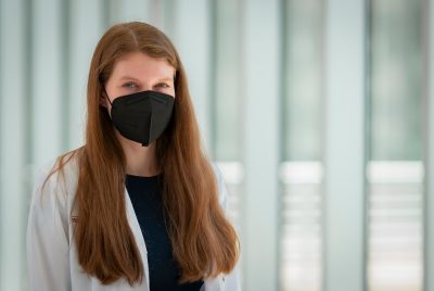 Woman wearing a white doctor's jacket and mask.