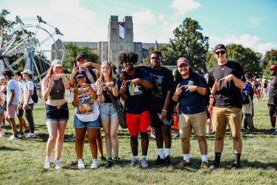 Students at Virginia Tech posing for a photo while making the letters V and T with fingers.